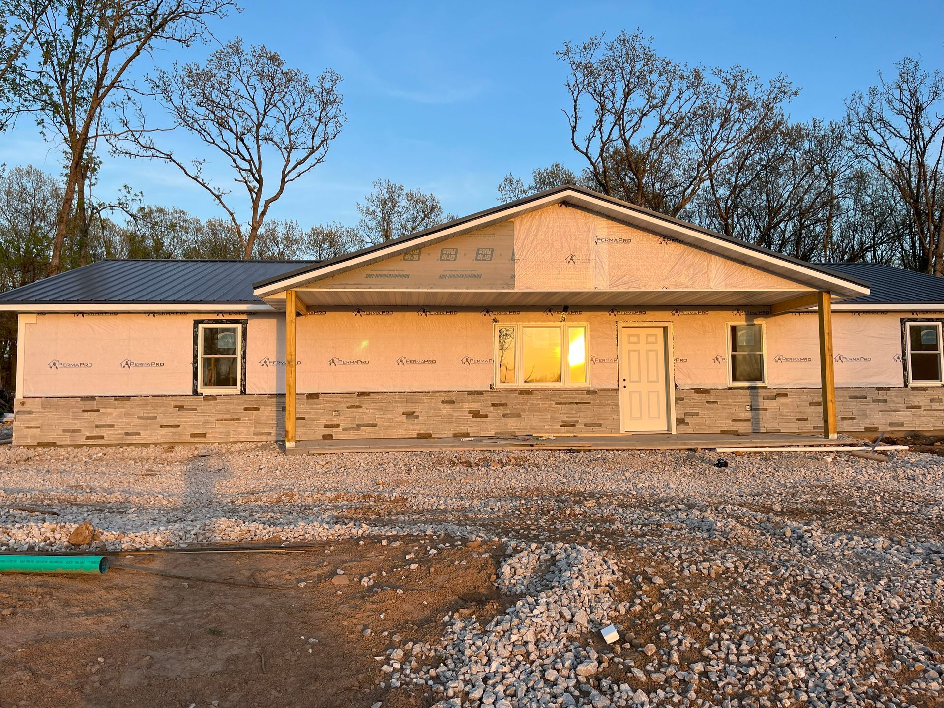 A house is being built in a dirt field with trees in the background.