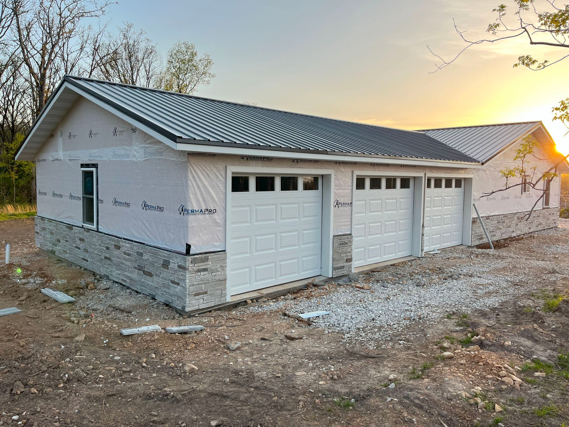 A garage under construction with three garage doors and a roof.