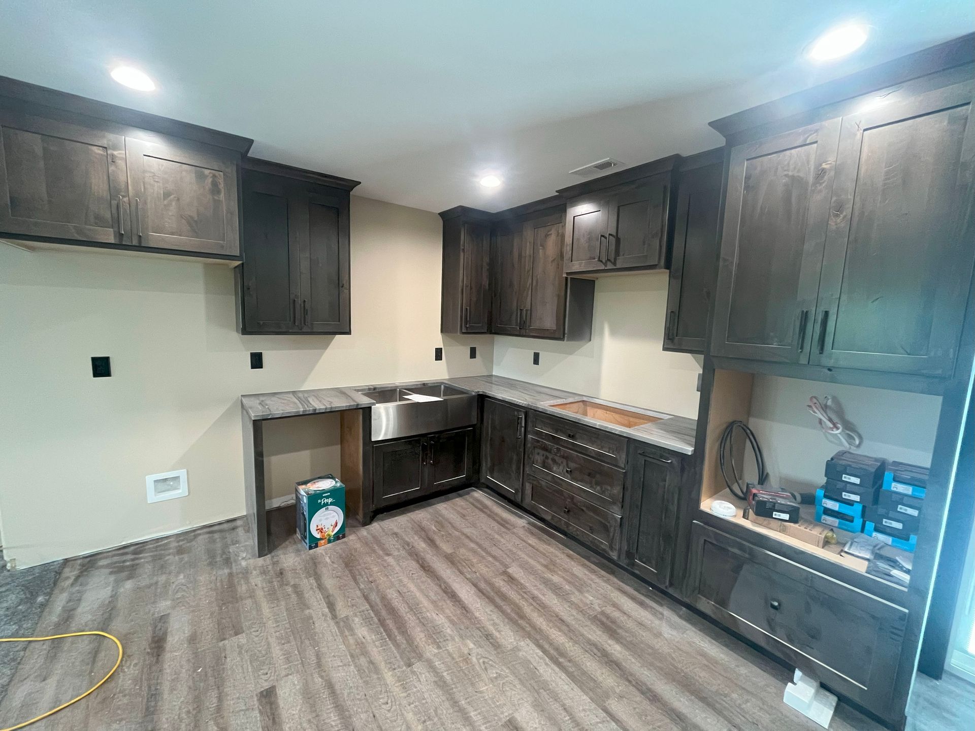 A kitchen with a sink , cabinets , and hardwood floors is being remodeled.
