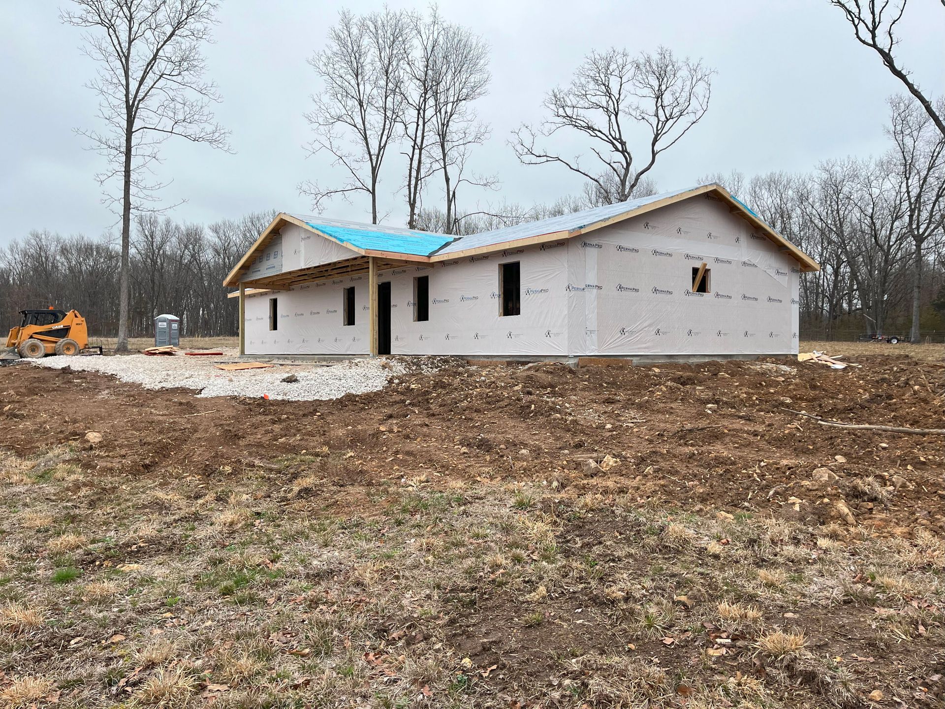 A house is being built in a field with a blue roof.