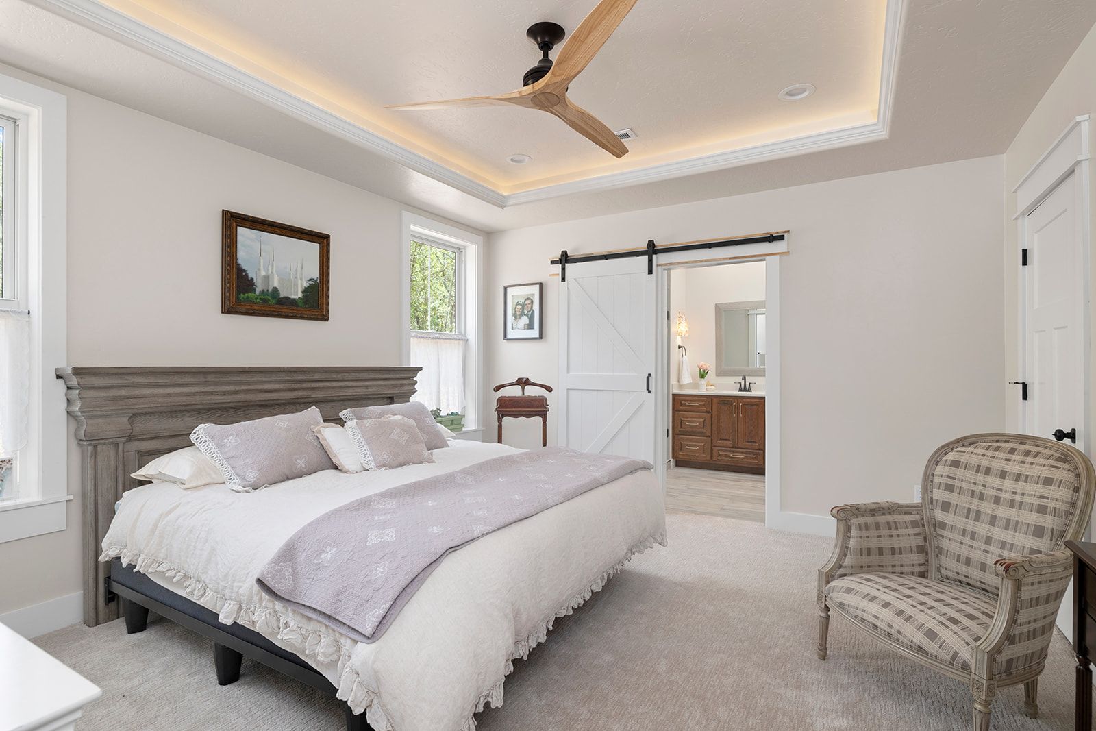 A bedroom with a large bed , chair and ceiling fan.