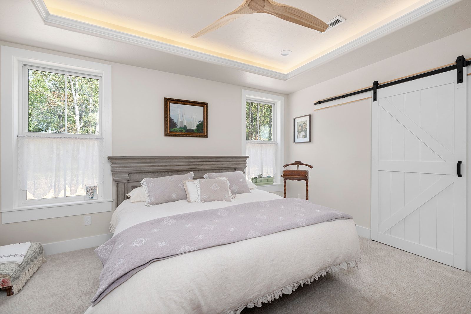 A bedroom with a bed , sliding barn doors , and a ceiling fan.