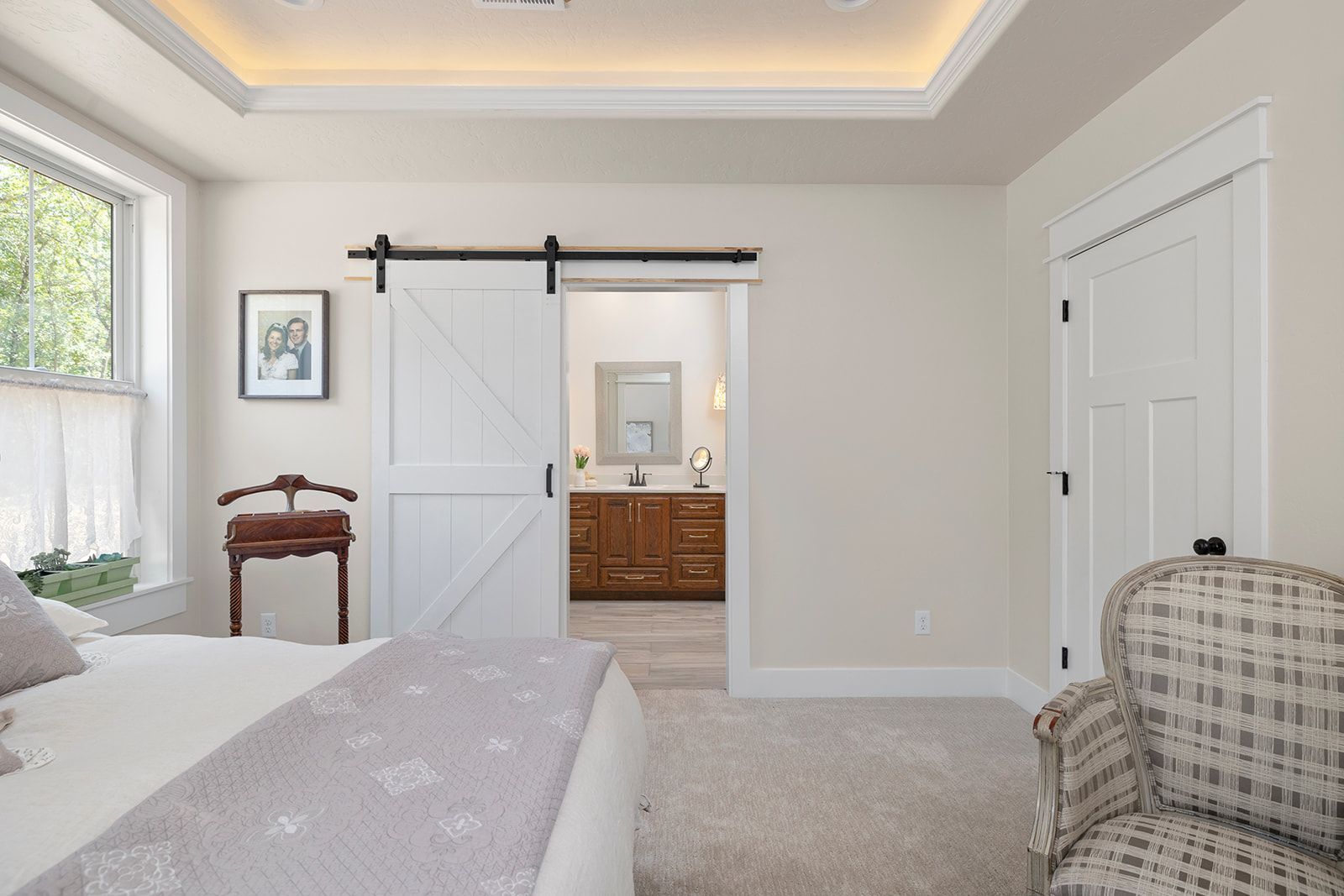 A bedroom with a sliding barn door leading to a bathroom.