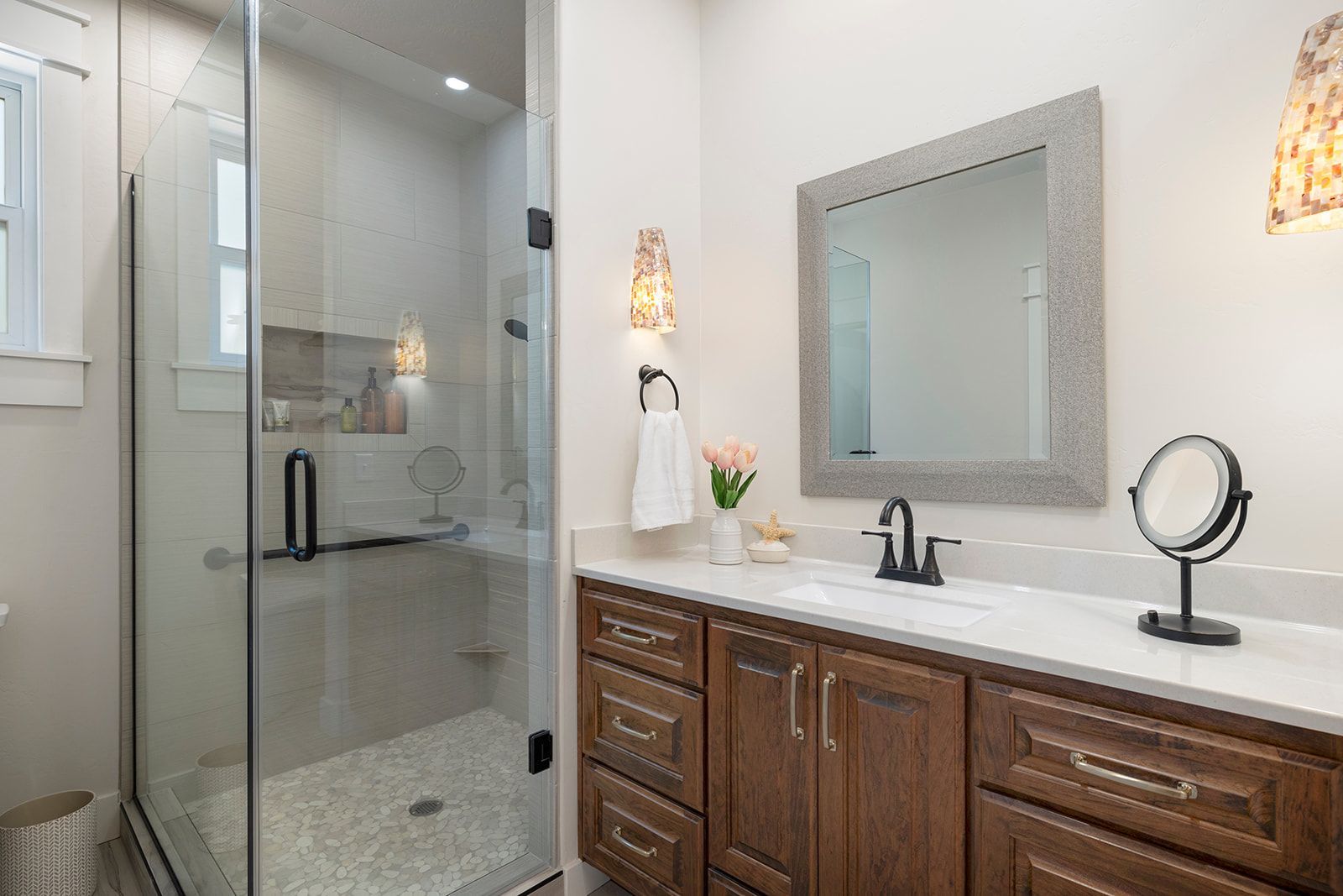 A bathroom with a sink , mirror and walk in shower.
