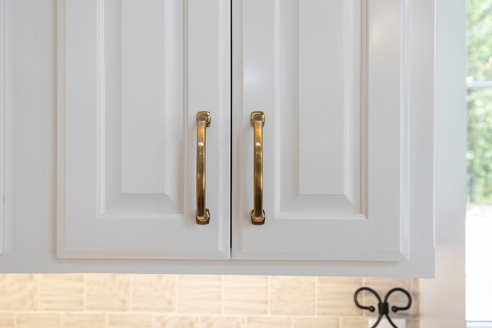 A kitchen with white cabinets and gold handles.
