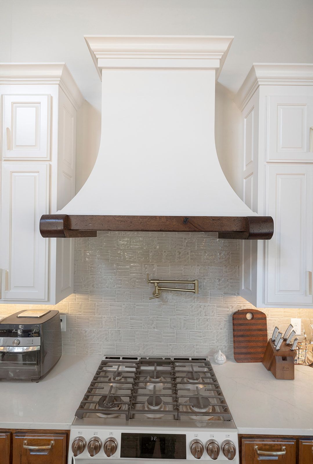 A kitchen with a stove and a hood above it.