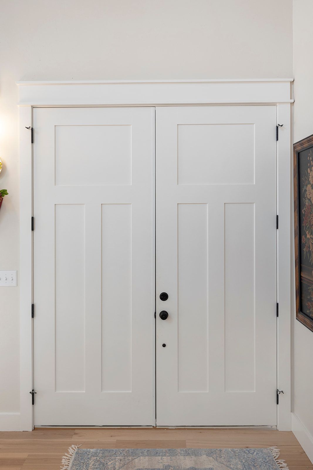 A pair of white doors with black knobs in a hallway.