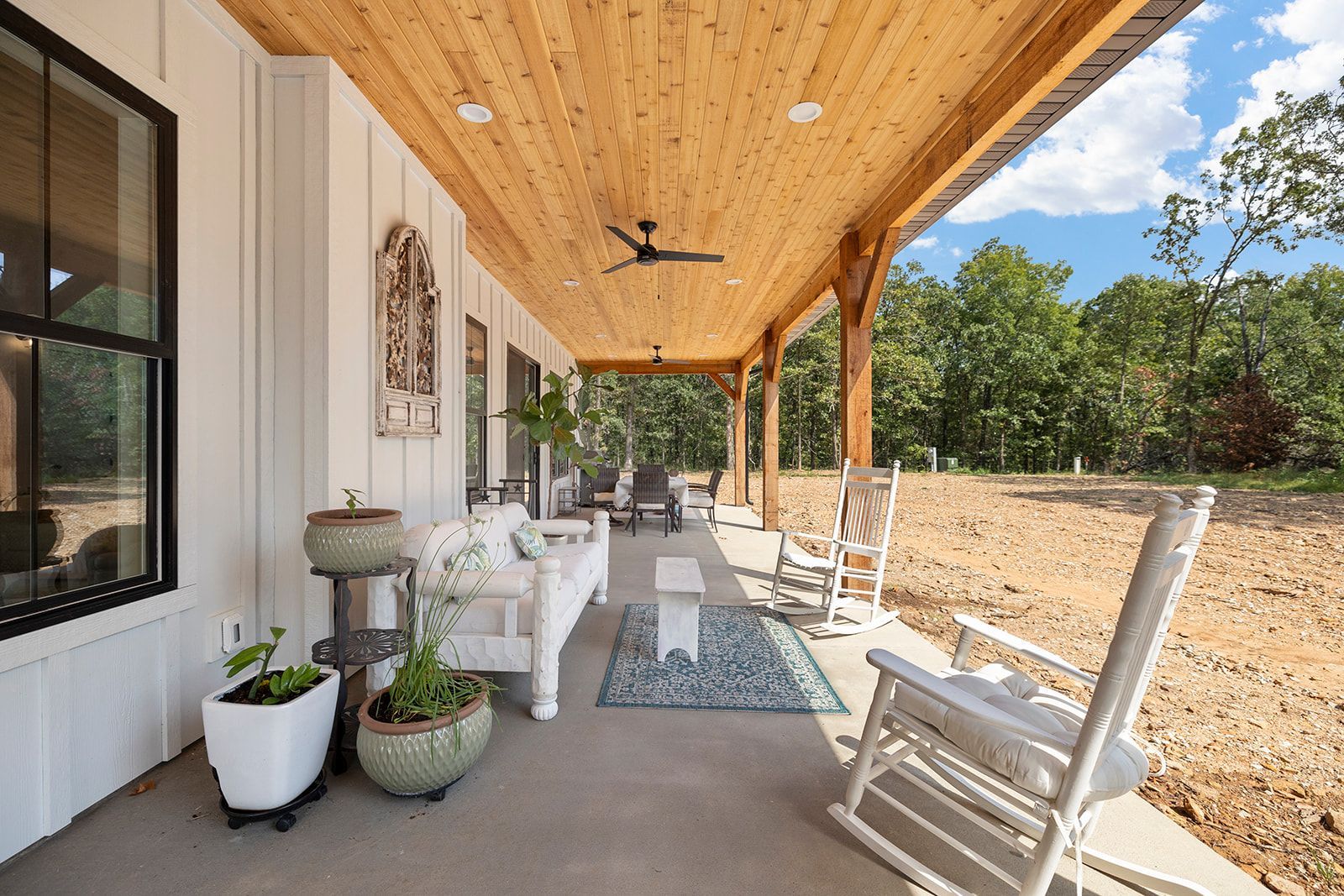 A porch with rocking chairs , a couch , and a ceiling fan.