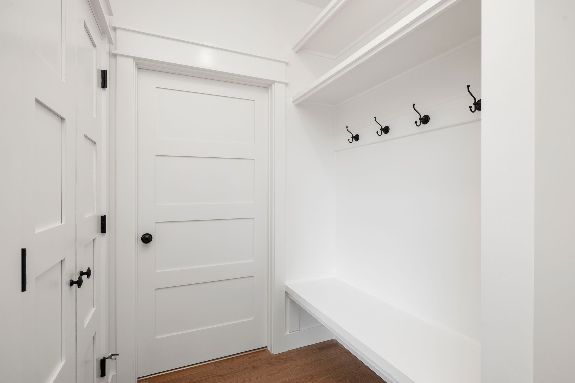 A hallway with a bench and hooks on the wall.