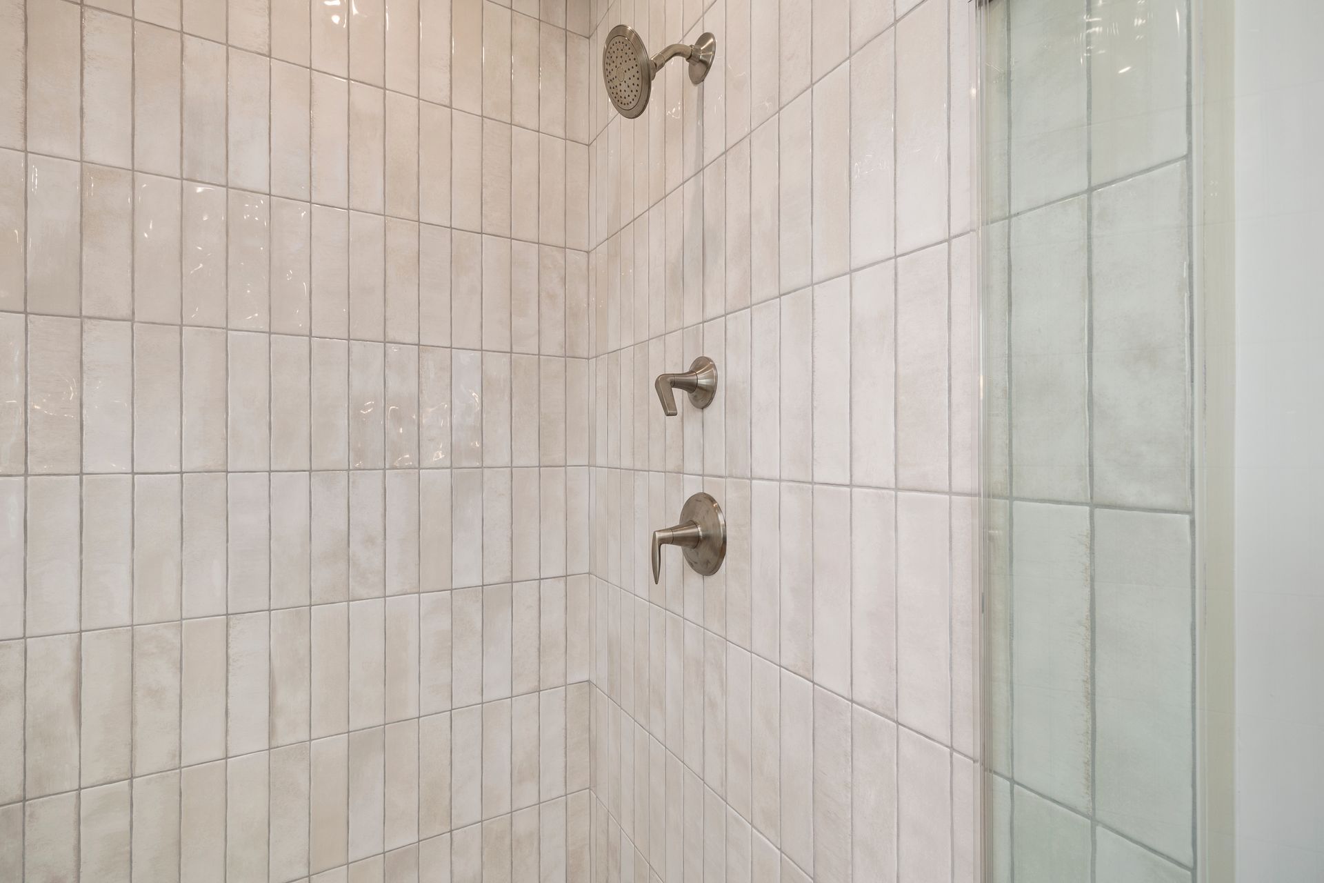 A shower with two shower heads and a glass door in a bathroom.