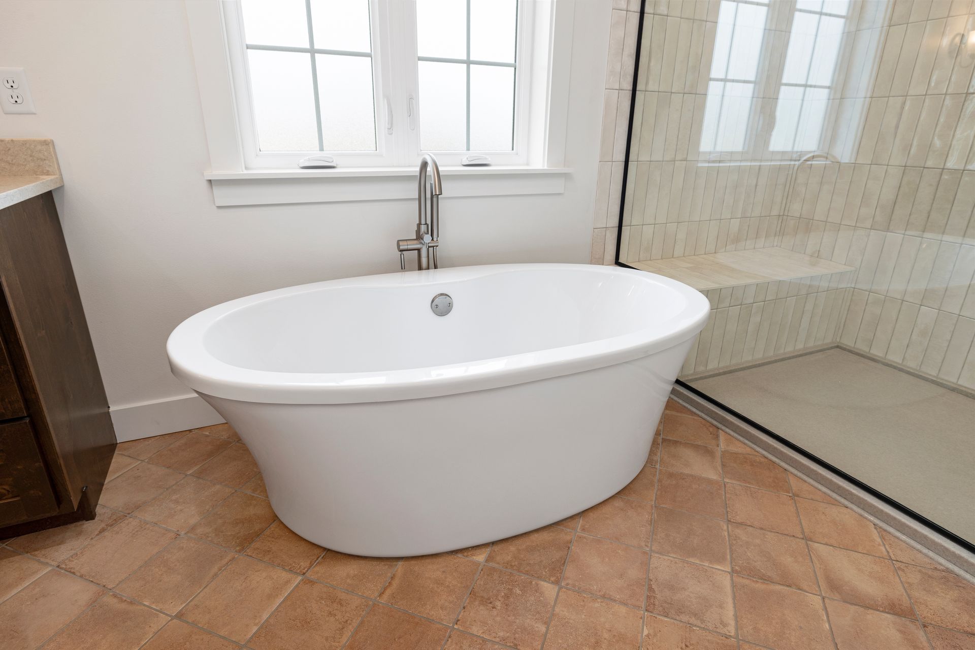 A white bathtub is sitting in a bathroom next to a walk in shower.