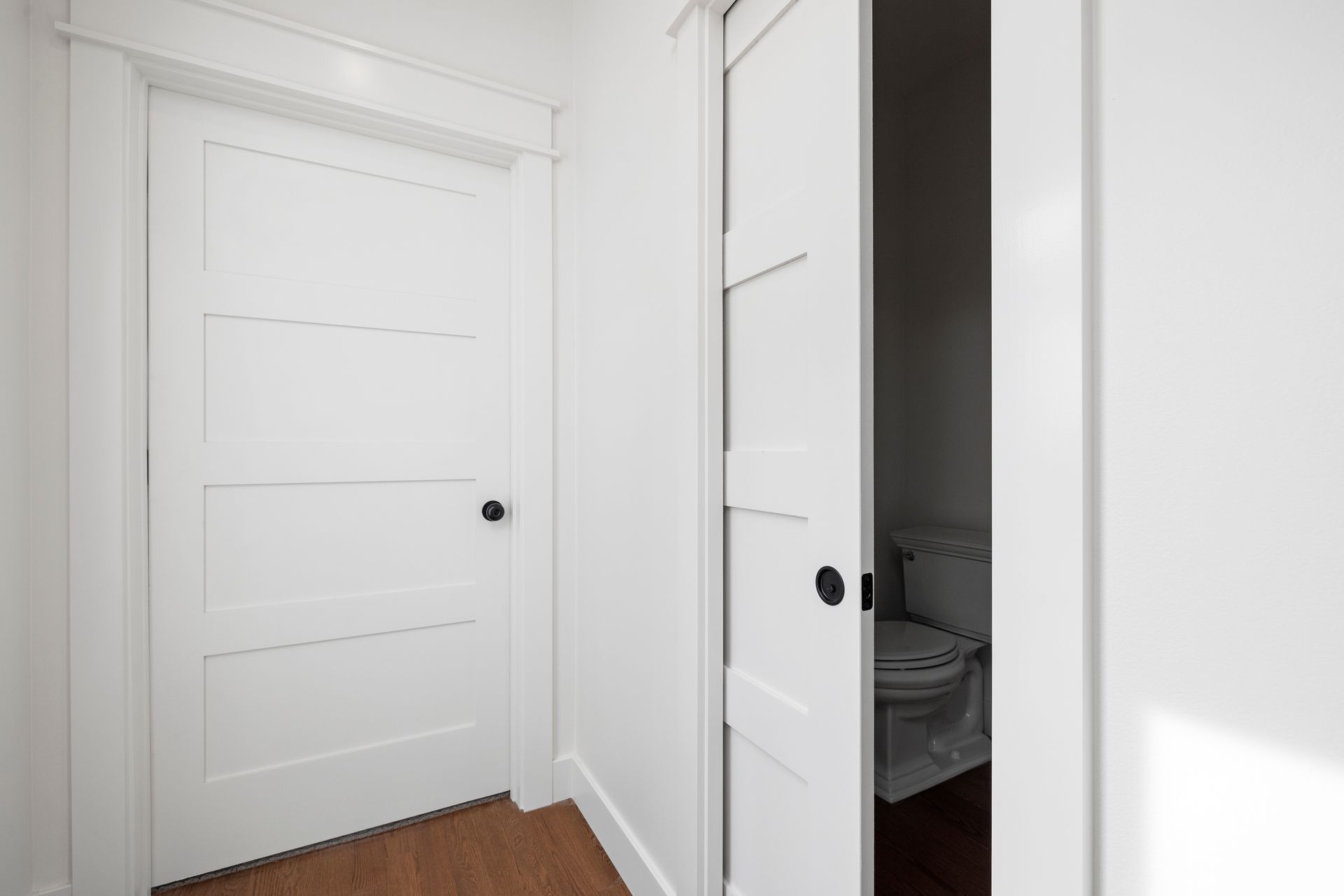 A white door is open to a bathroom with a toilet.