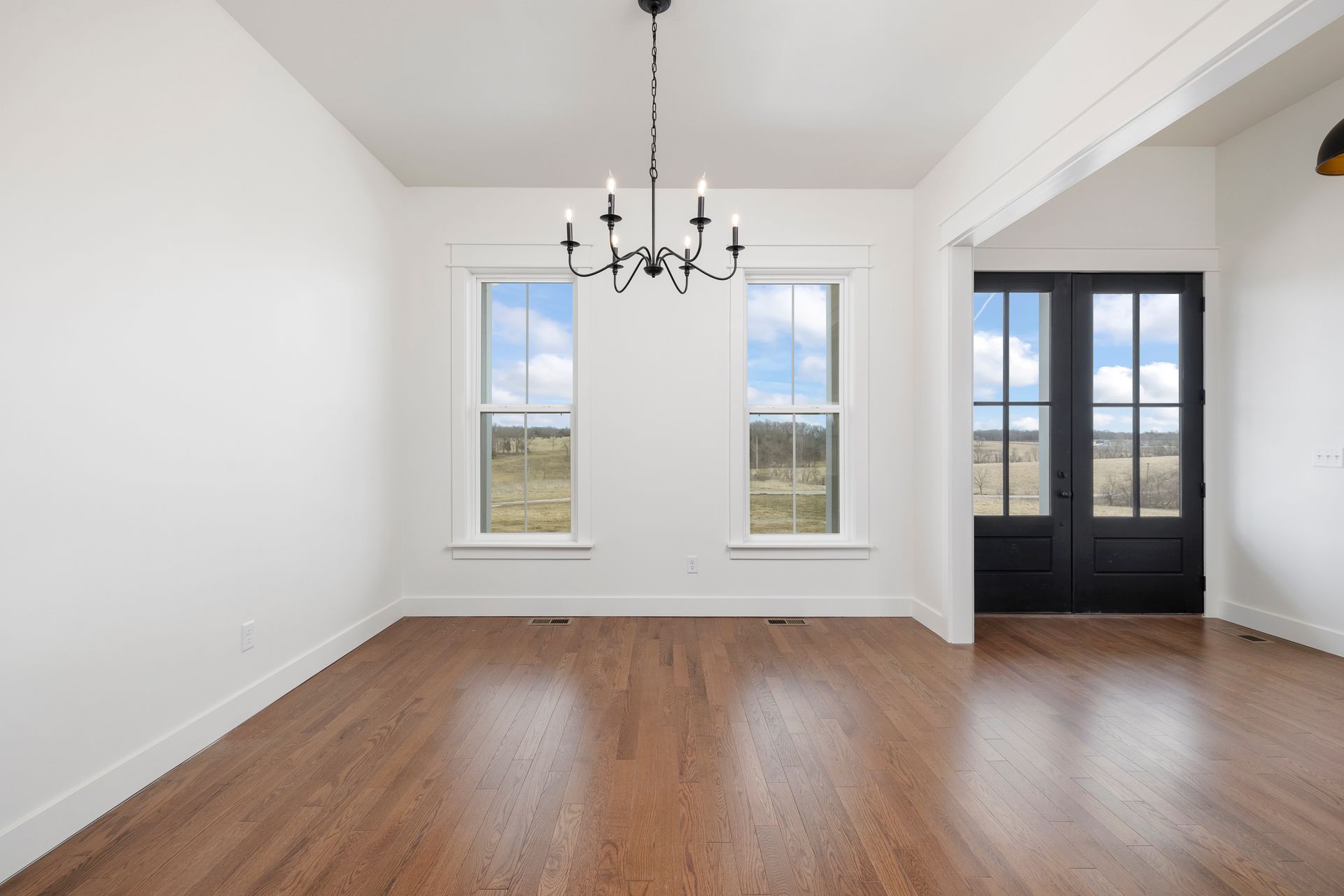 An empty room with hardwood floors and a chandelier