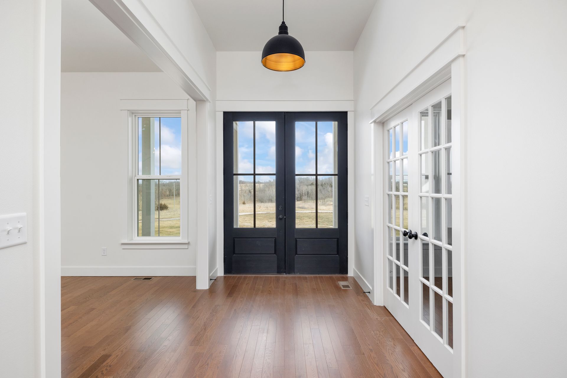 A hallway in a house with a black door and french doors.