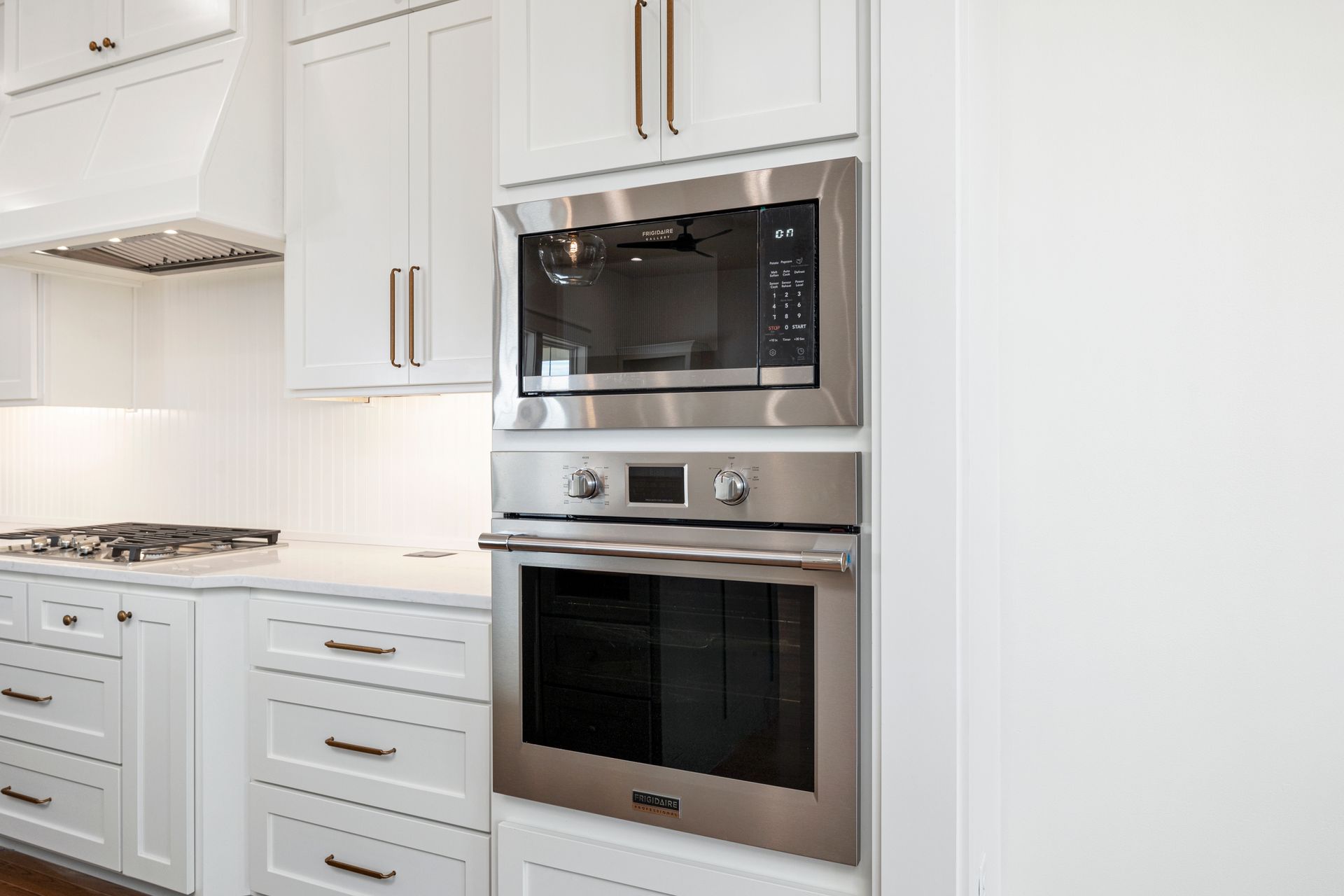 A kitchen with white cabinets and a stainless steel oven and microwave.