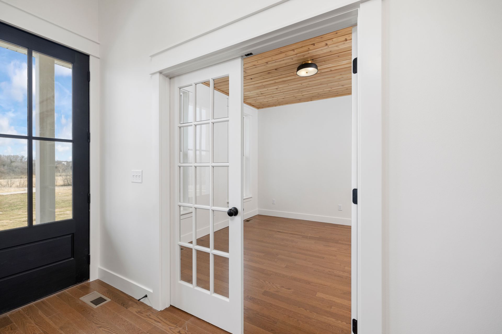 A room with a french door and a wooden ceiling.