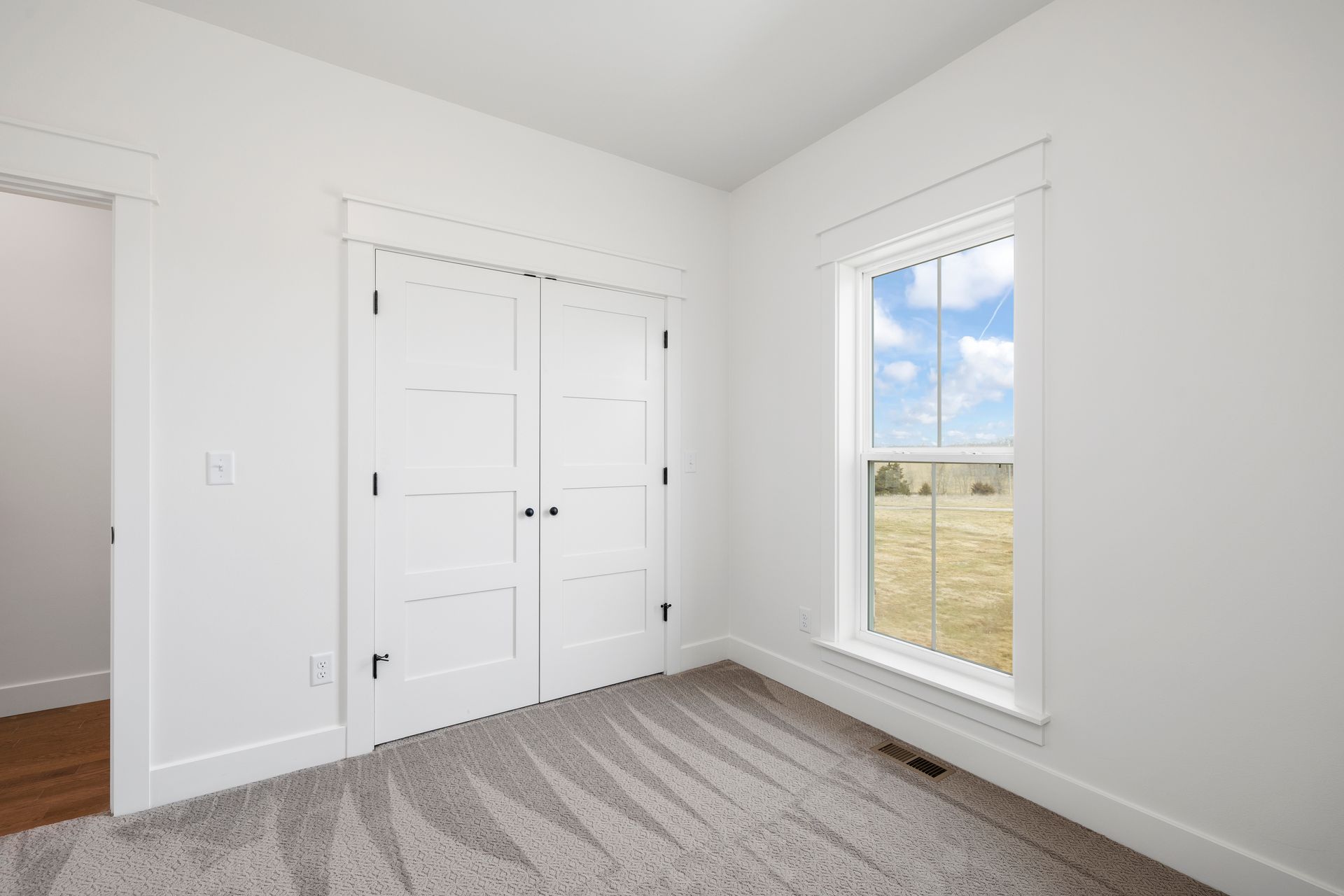 An empty bedroom with white walls and a window.