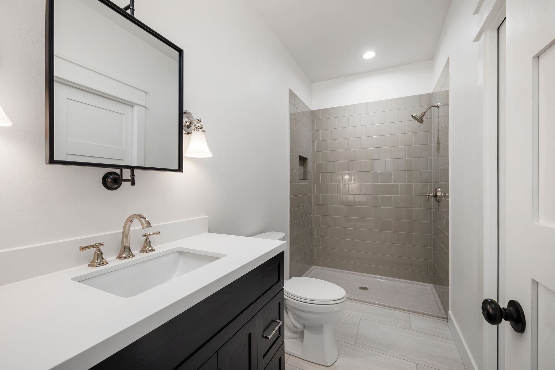 A bathroom with a toilet , sink , mirror and walk in shower.