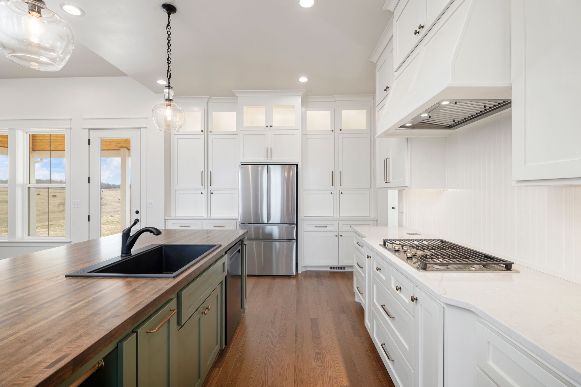 A kitchen with white cabinets , stainless steel appliances , a sink , and a stove top oven.