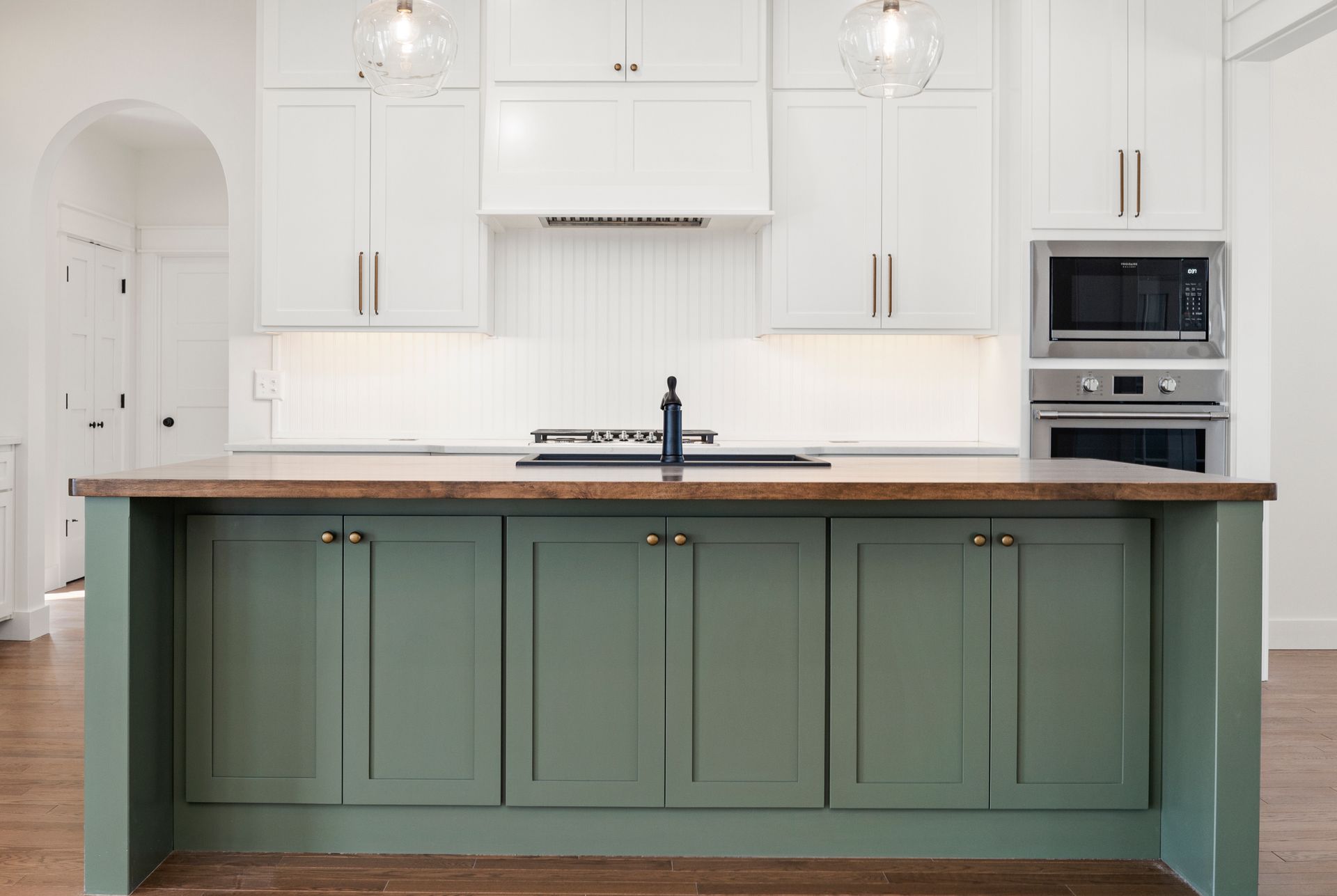 A kitchen with green cabinets and white cabinets and a large island.