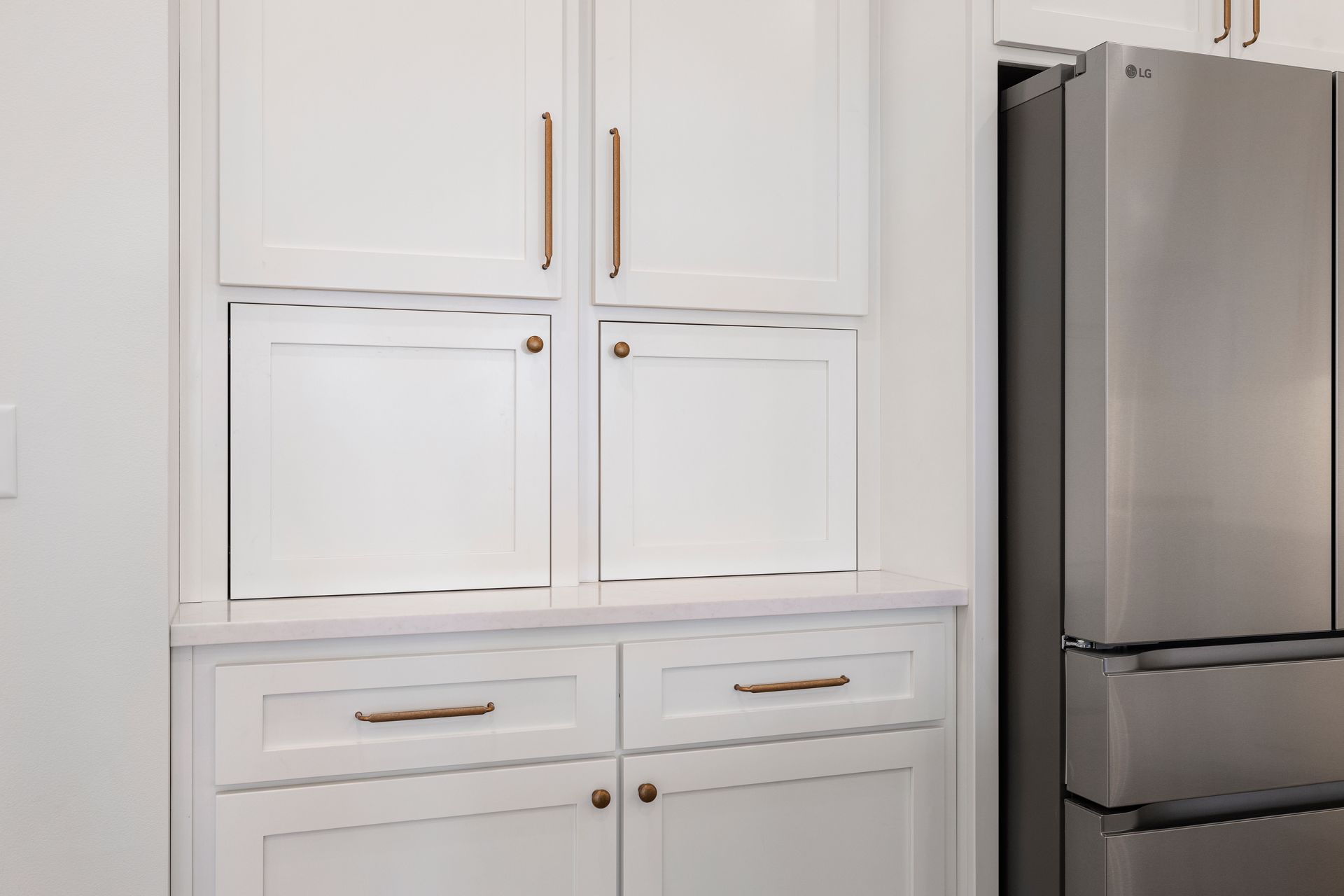 A kitchen with white cabinets and a stainless steel refrigerator.