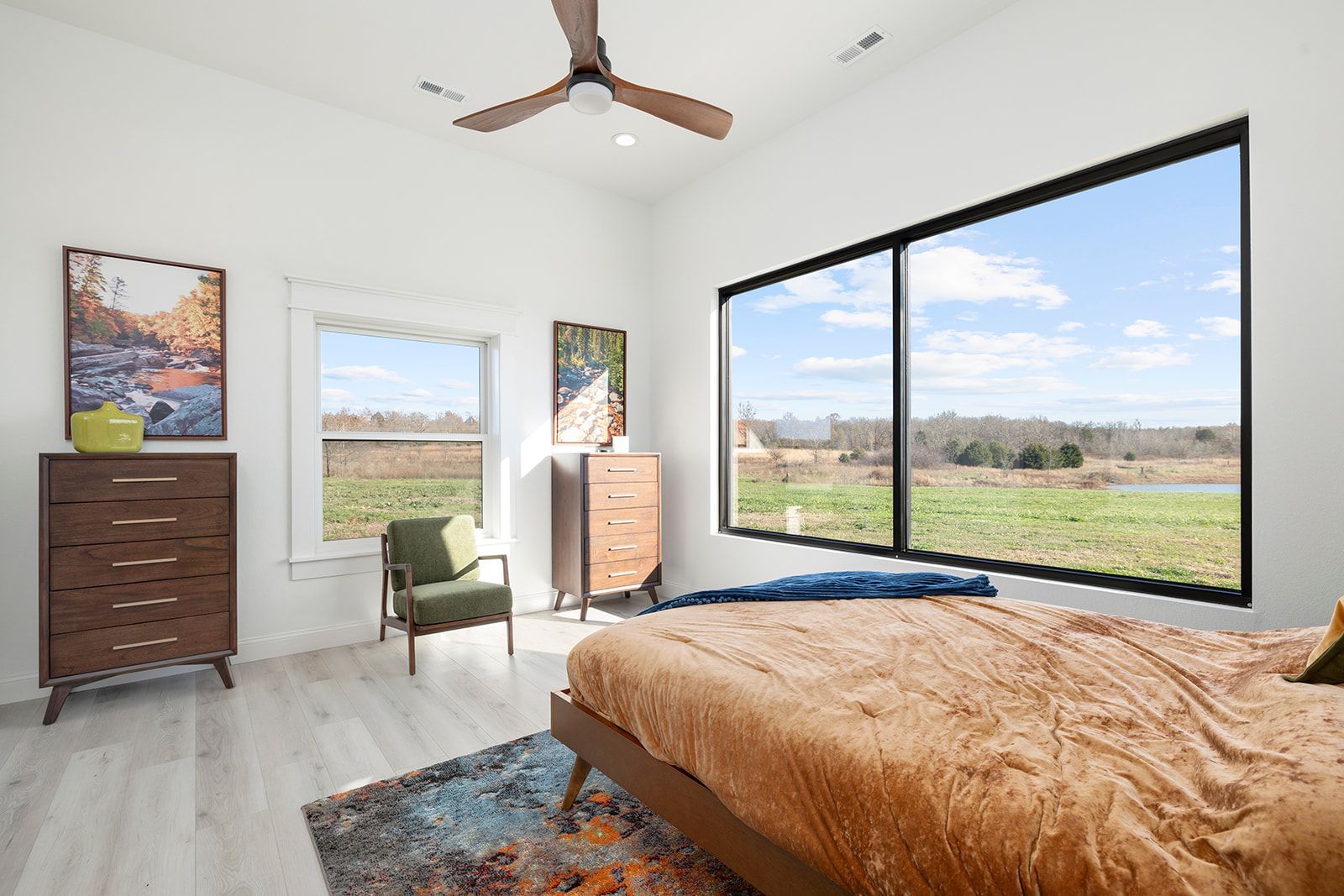 A bedroom with a bed , dresser , chair and ceiling fan.