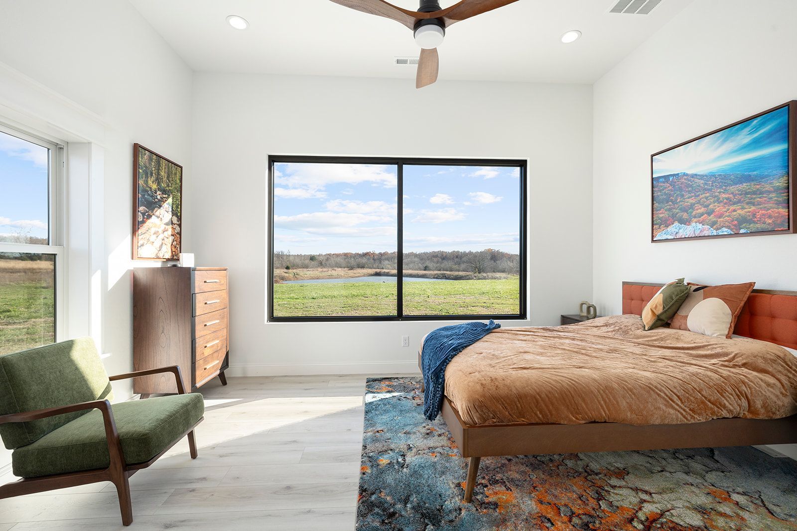A bedroom with a bed , chair , dresser and ceiling fan.
