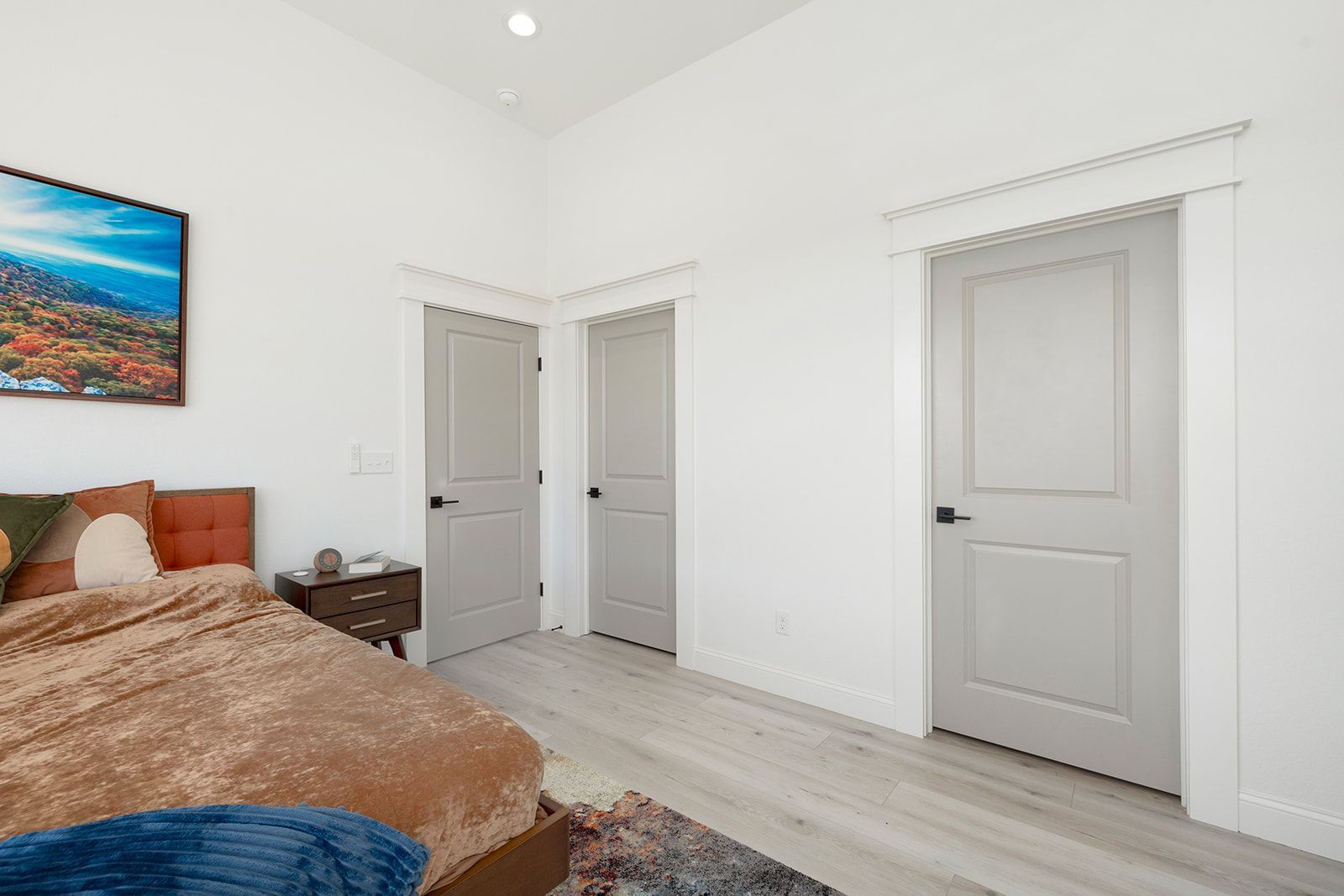 A bedroom with a bed , nightstand , and a picture on the wall.
