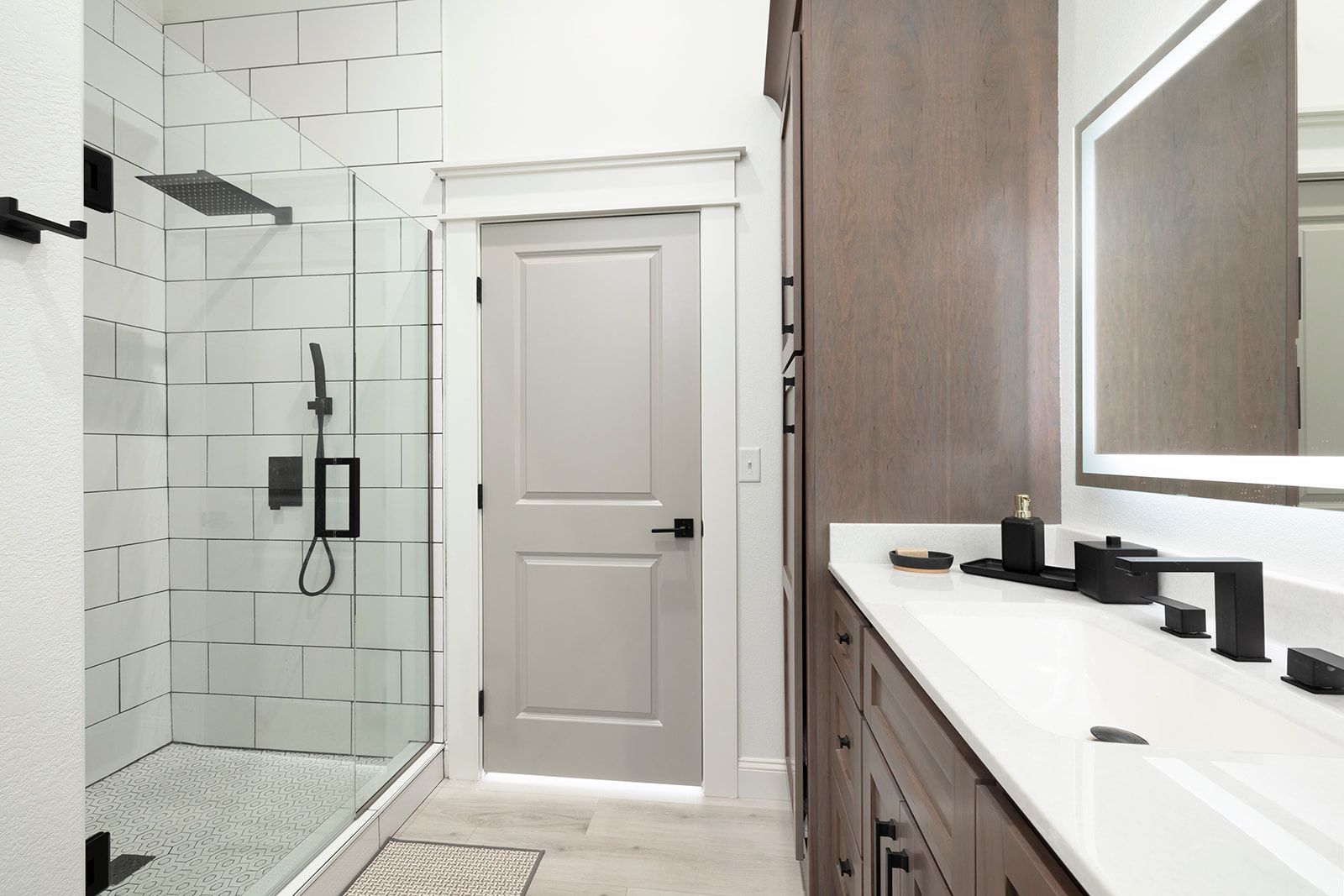 A bathroom with a walk in shower , sink and mirror.