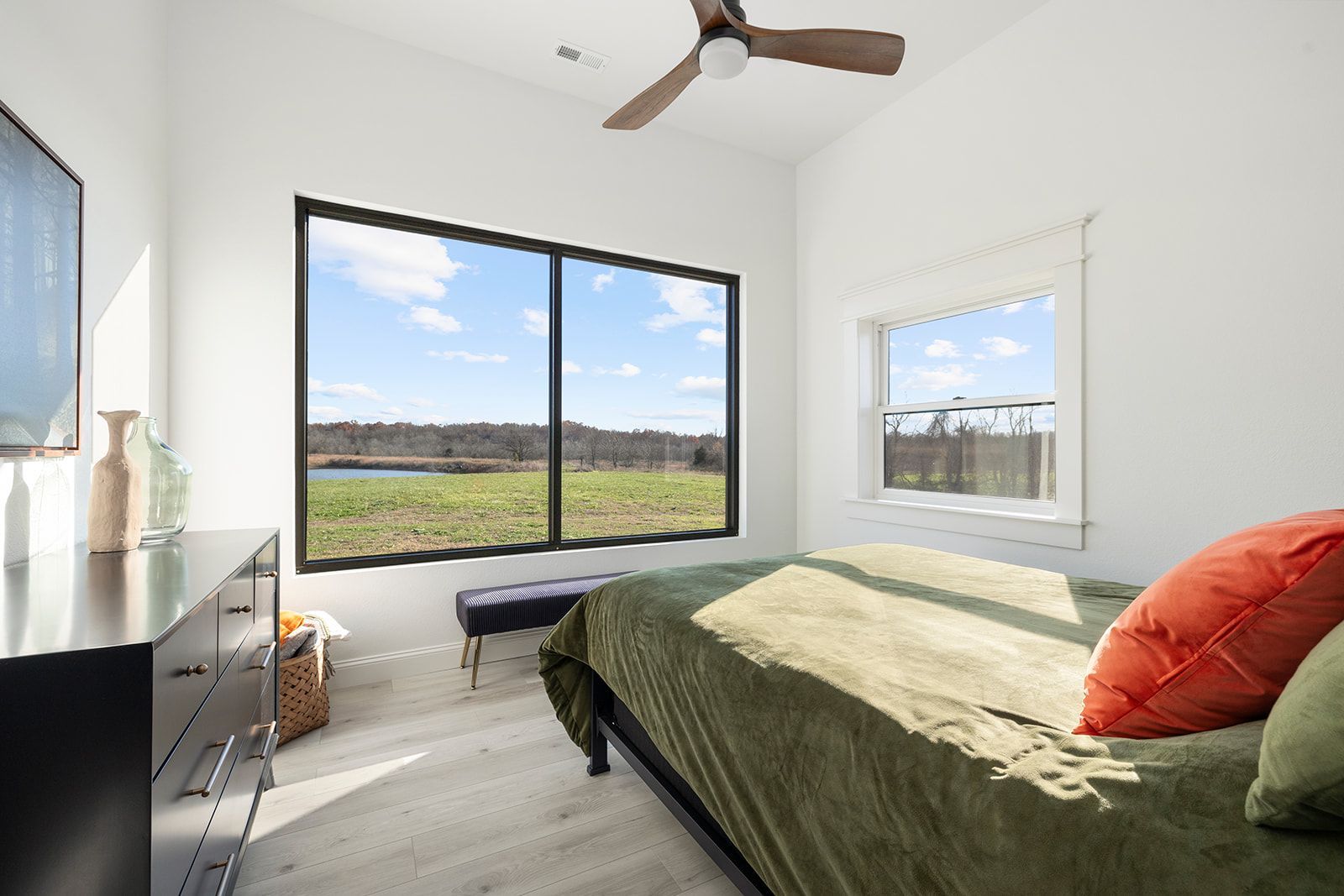 A bedroom with a bed , dresser , television and a ceiling fan.