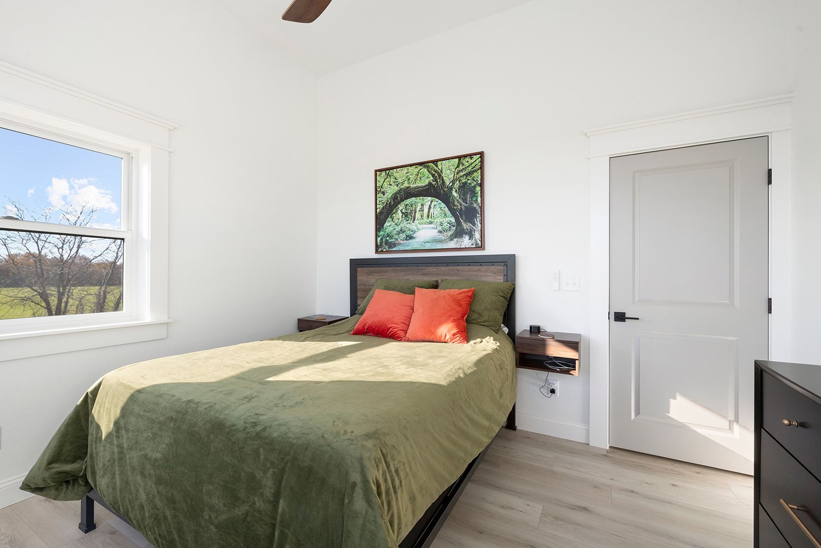 A bedroom with a bed , dresser , window and ceiling fan.