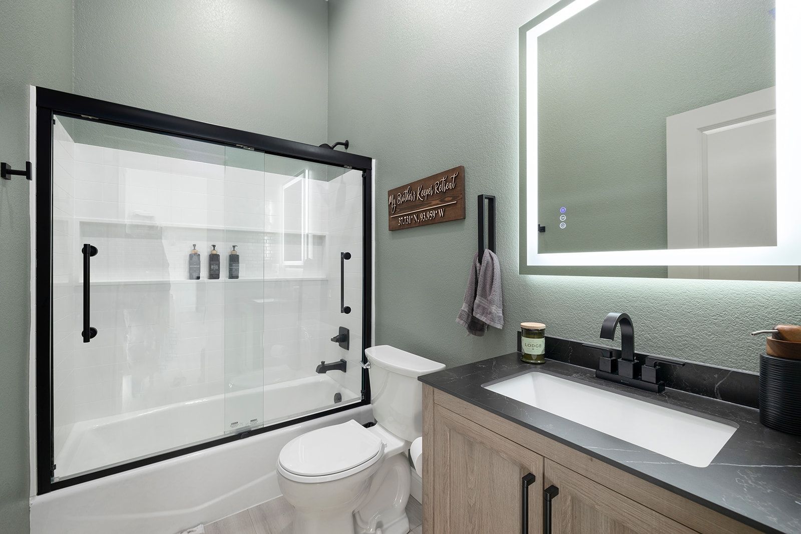 A bathroom with a toilet , sink , shower and mirror.