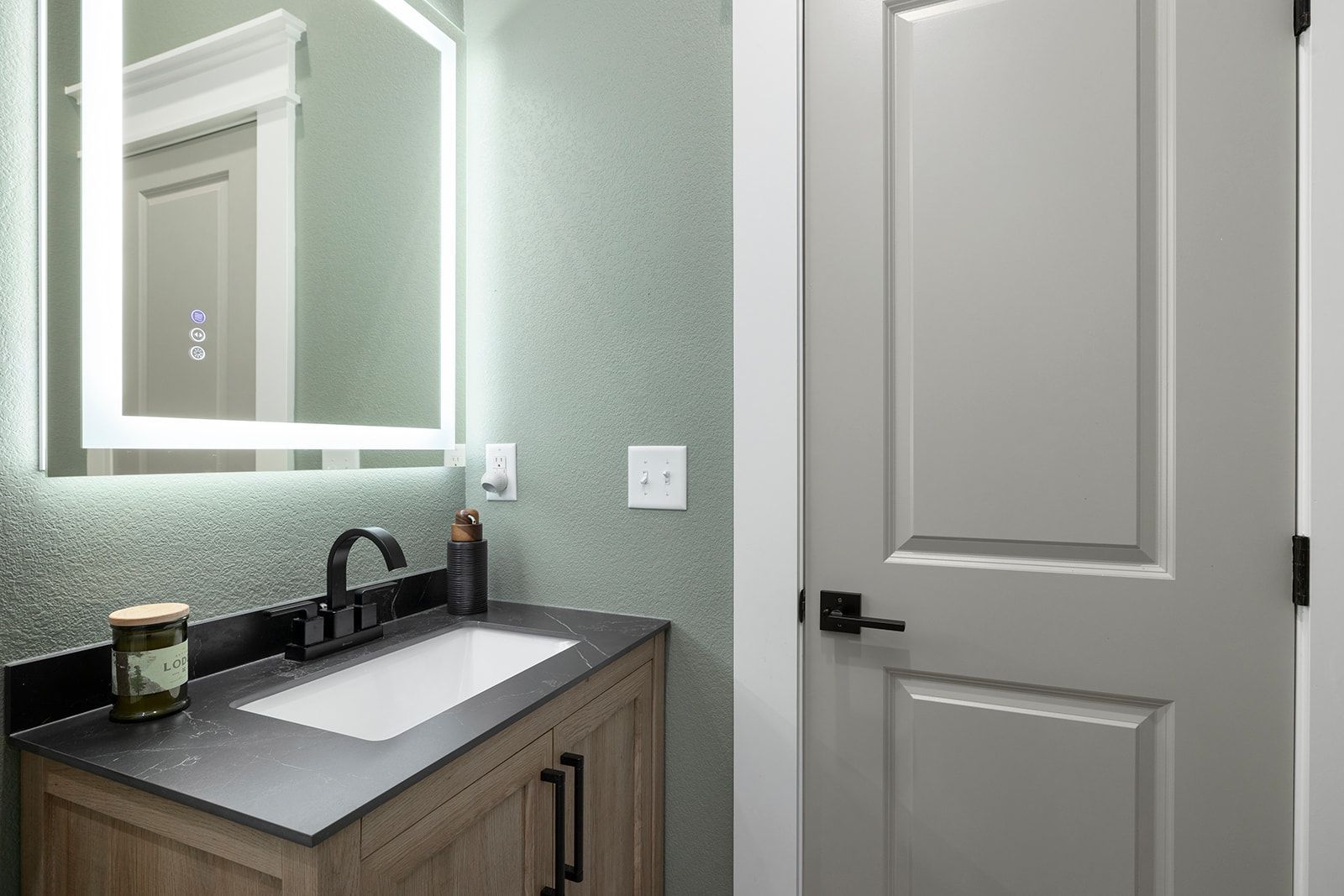 A bathroom with a sink , mirror and door.