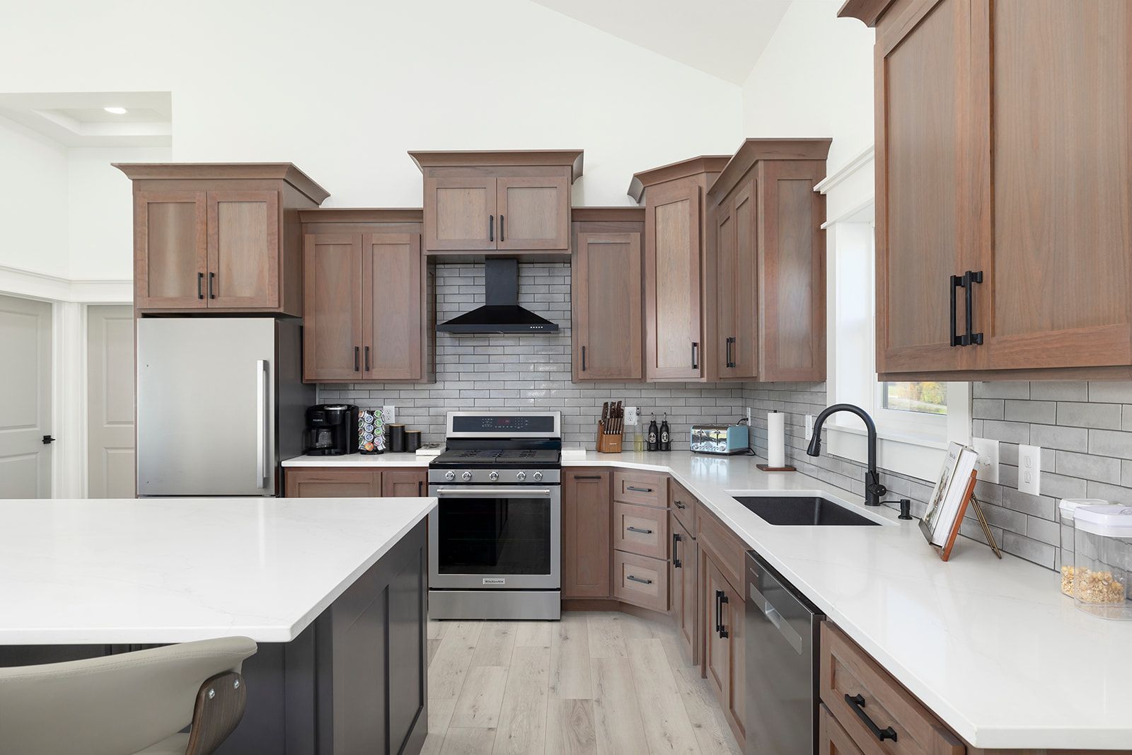 A kitchen with stainless steel appliances , wooden cabinets , and white counter tops.