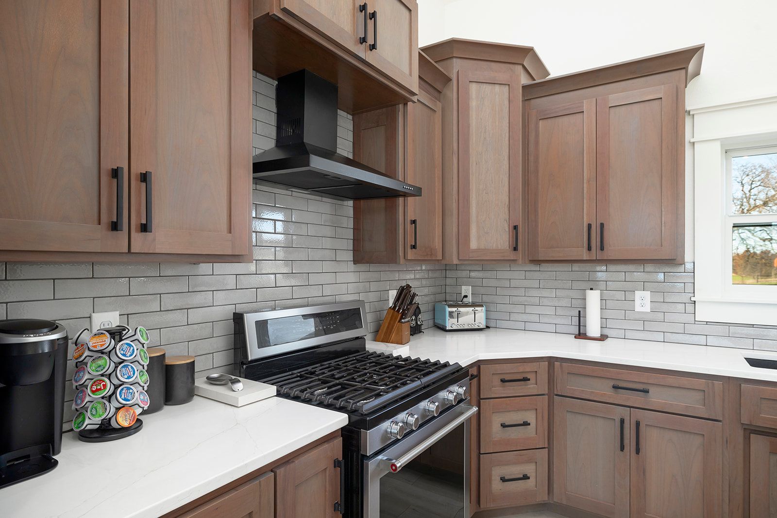 A kitchen with wooden cabinets , stainless steel appliances , and white counter tops.