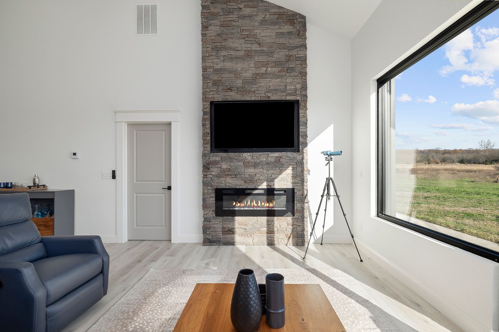 A living room with a fireplace , television , and large window.