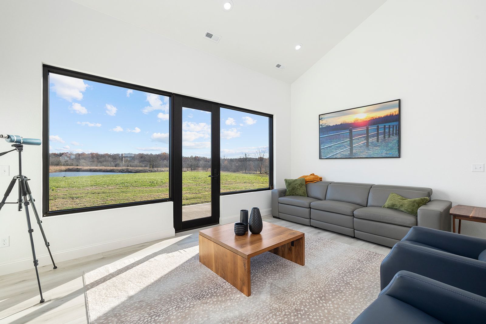 A living room with a couch , chairs , coffee table and a telescope.