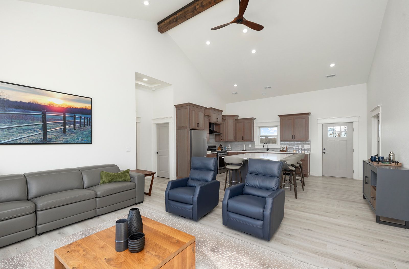 A living room with a couch , two chairs , a coffee table and a ceiling fan.