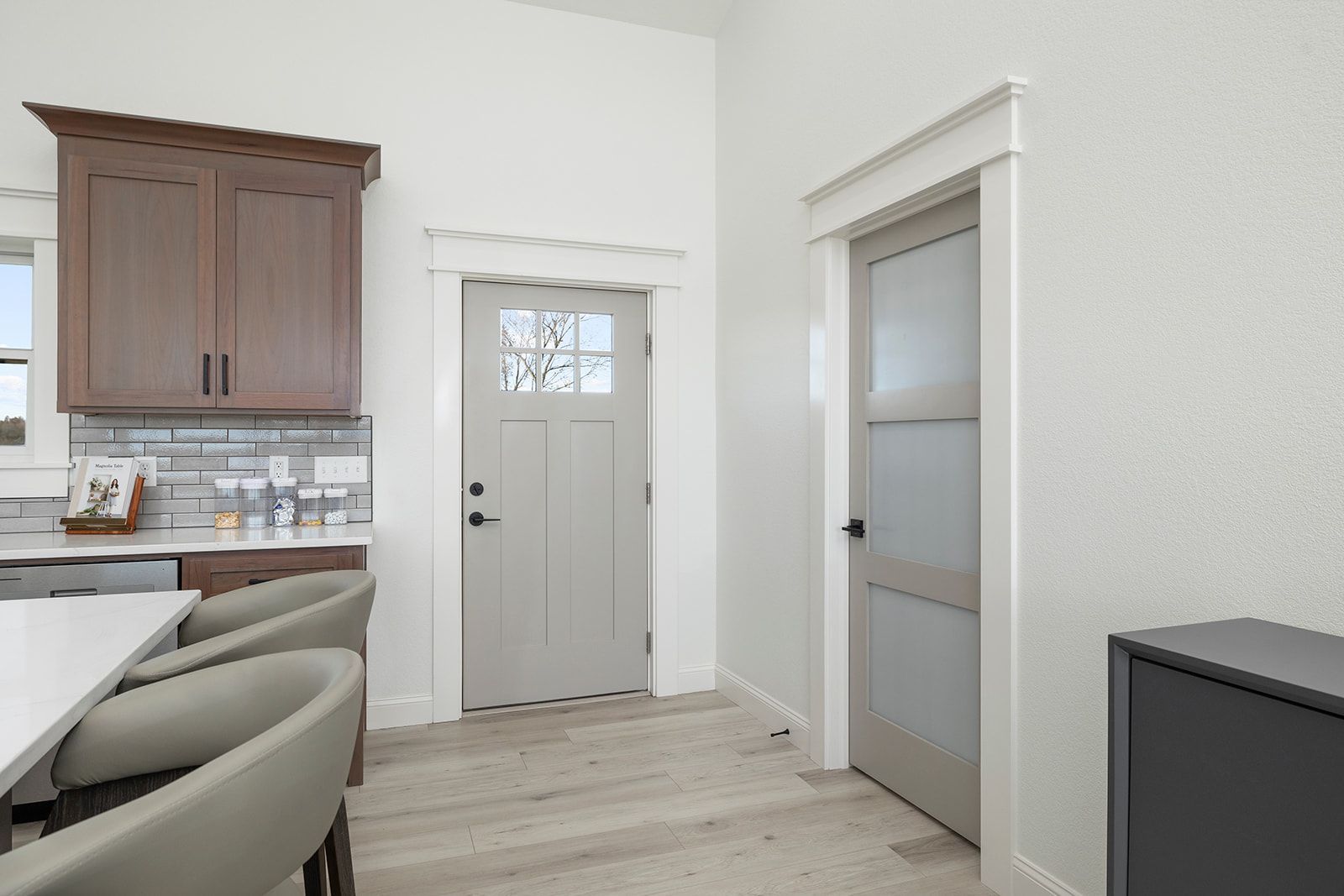 A kitchen with a gray door and brown cabinets.
