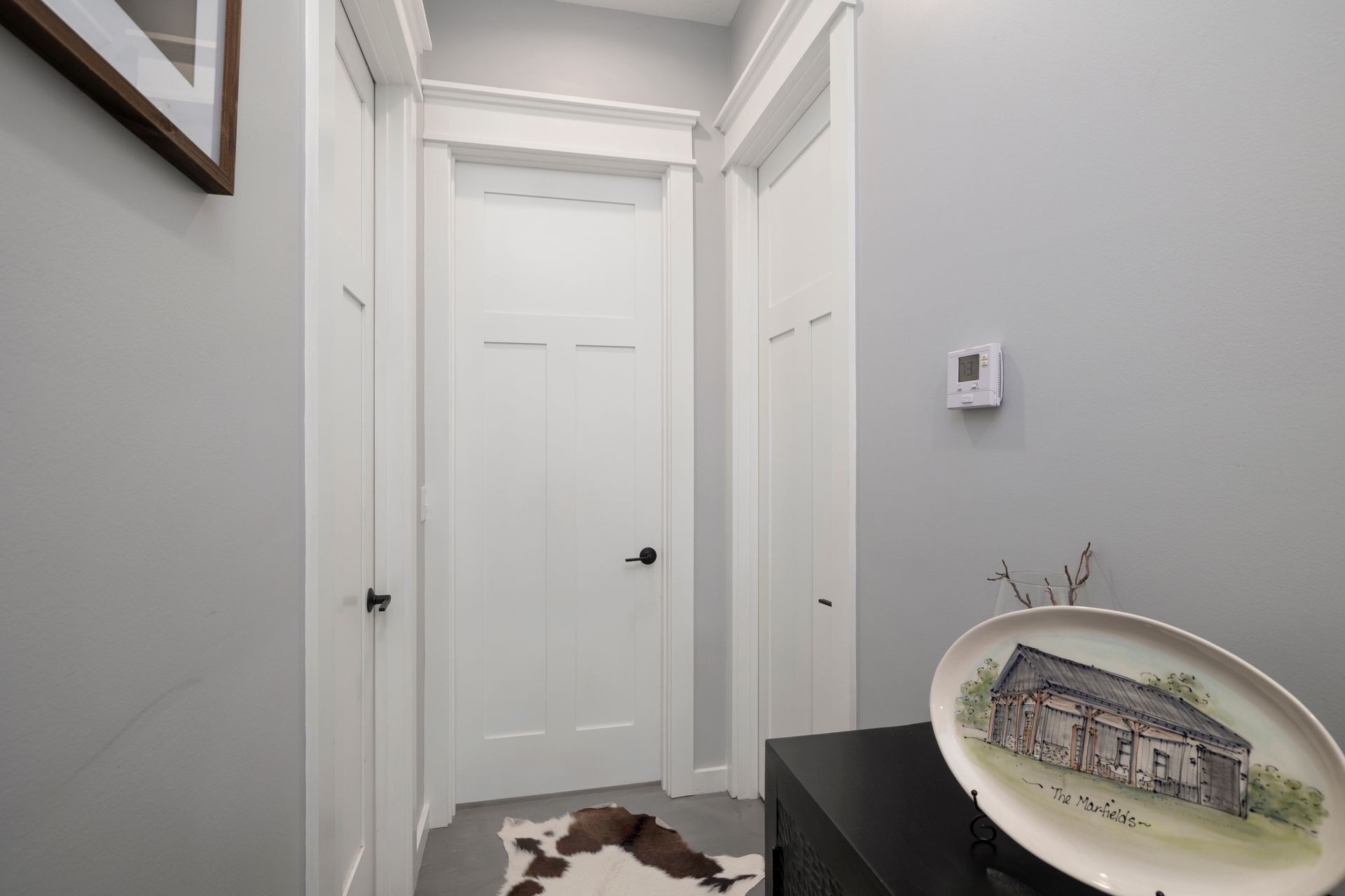 A hallway with white doors and a plate with a picture of a house on it.