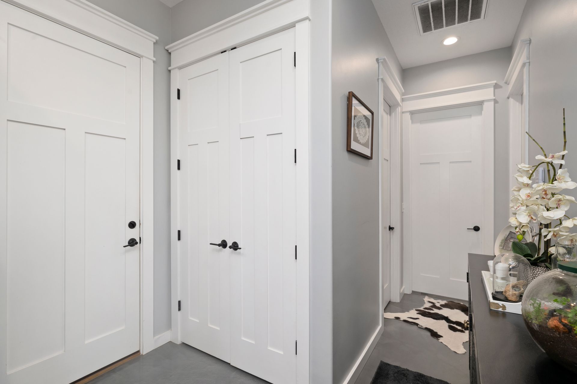 A hallway with white doors and a picture on the wall.