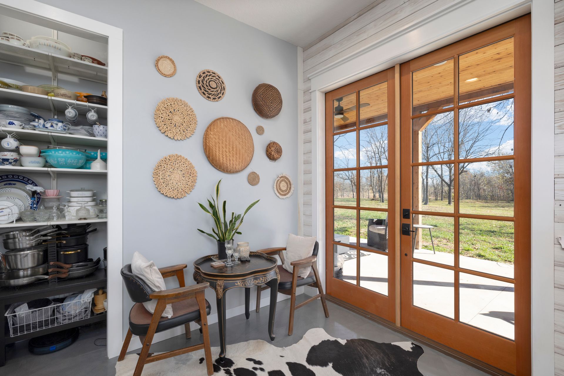 A room with a table and chairs and a cow print rug.