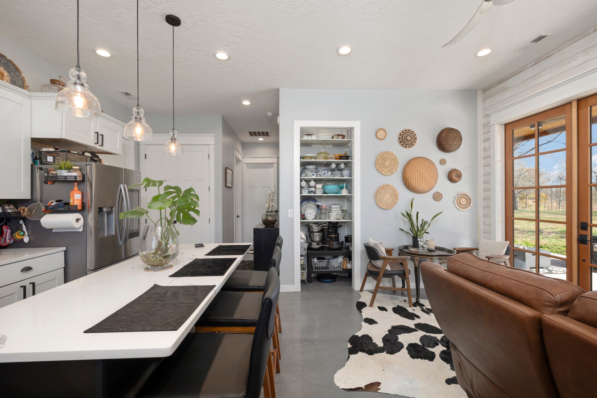 A kitchen and living room in a house with a cow print rug.