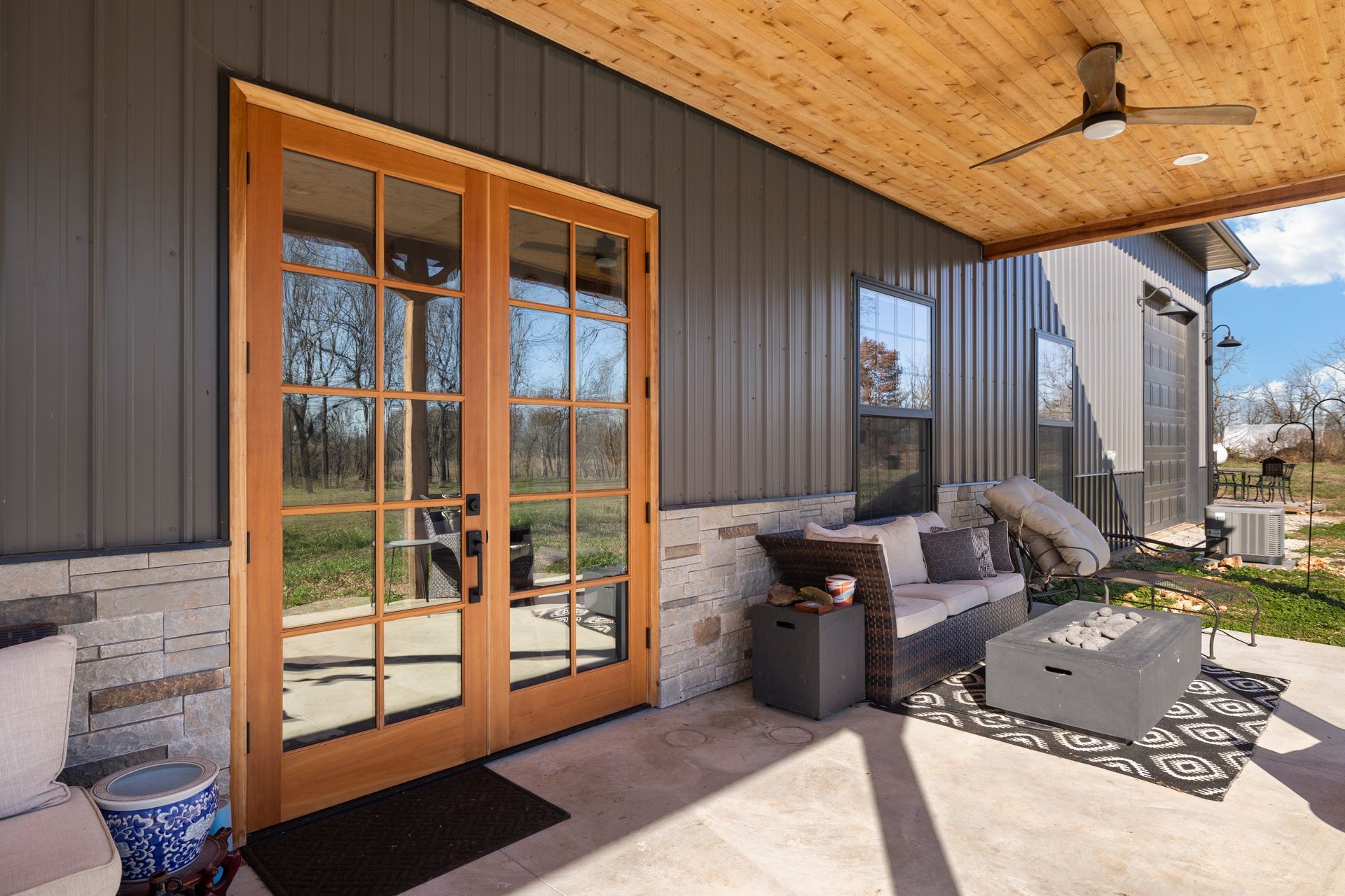 A porch with a couch , coffee table , and a ceiling fan.