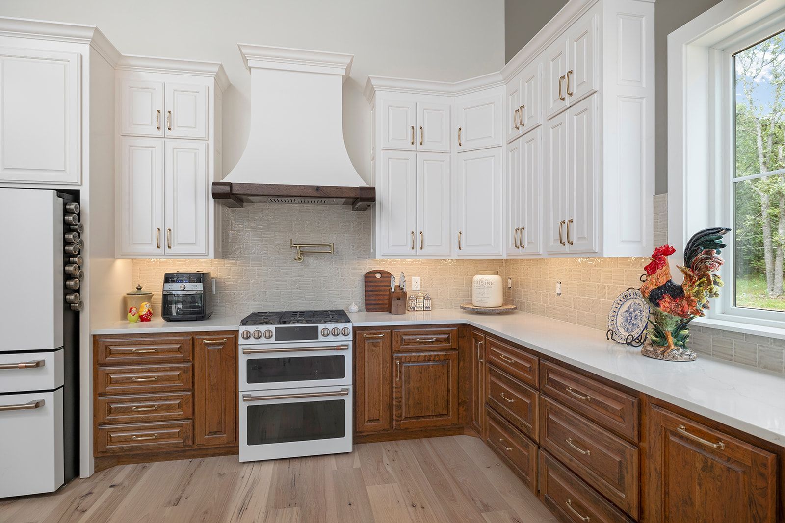 A kitchen with white cabinets , wooden cabinets , a stove , refrigerator , and a window.