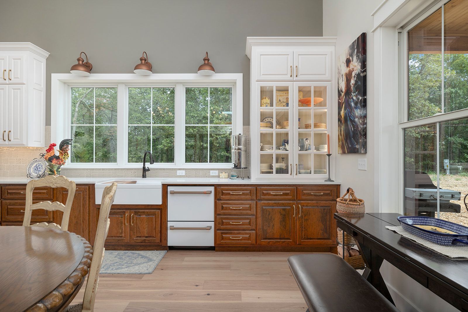 A kitchen with wooden cabinets , a sink , a table and a bench.
