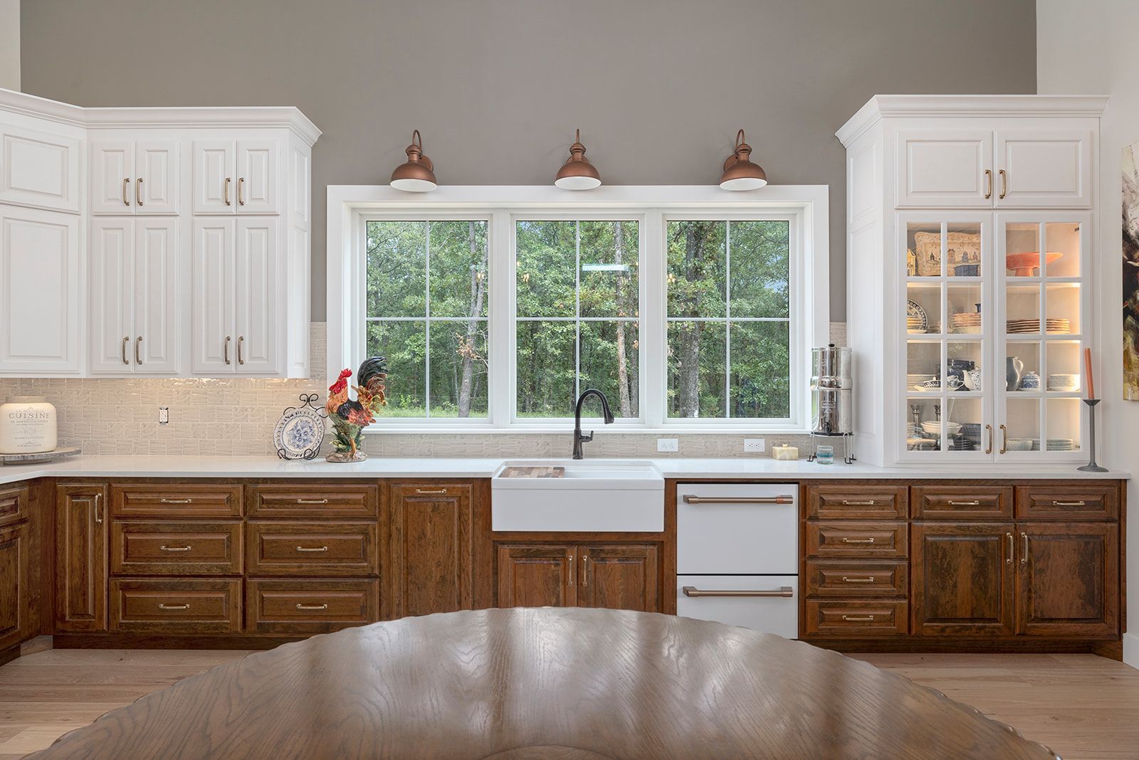A kitchen with white cabinets , wooden cabinets , a sink , and a table.