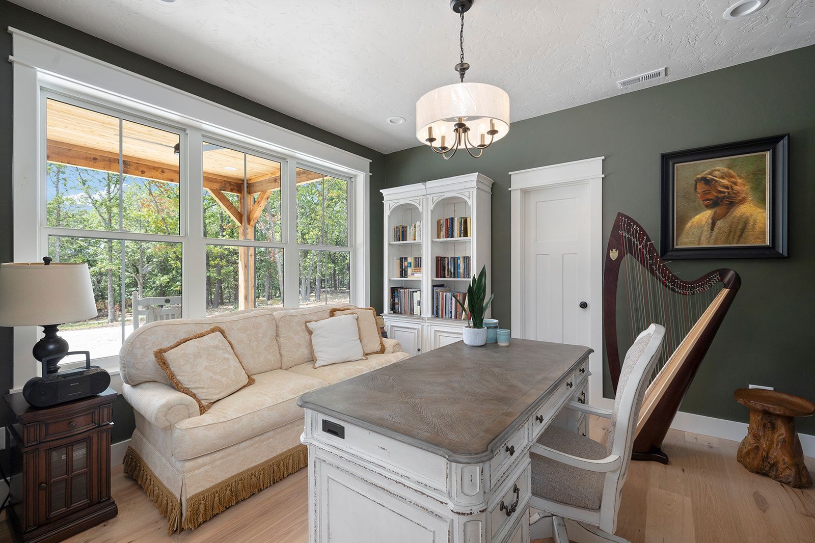A living room with a couch , desk , chairs and a harp.