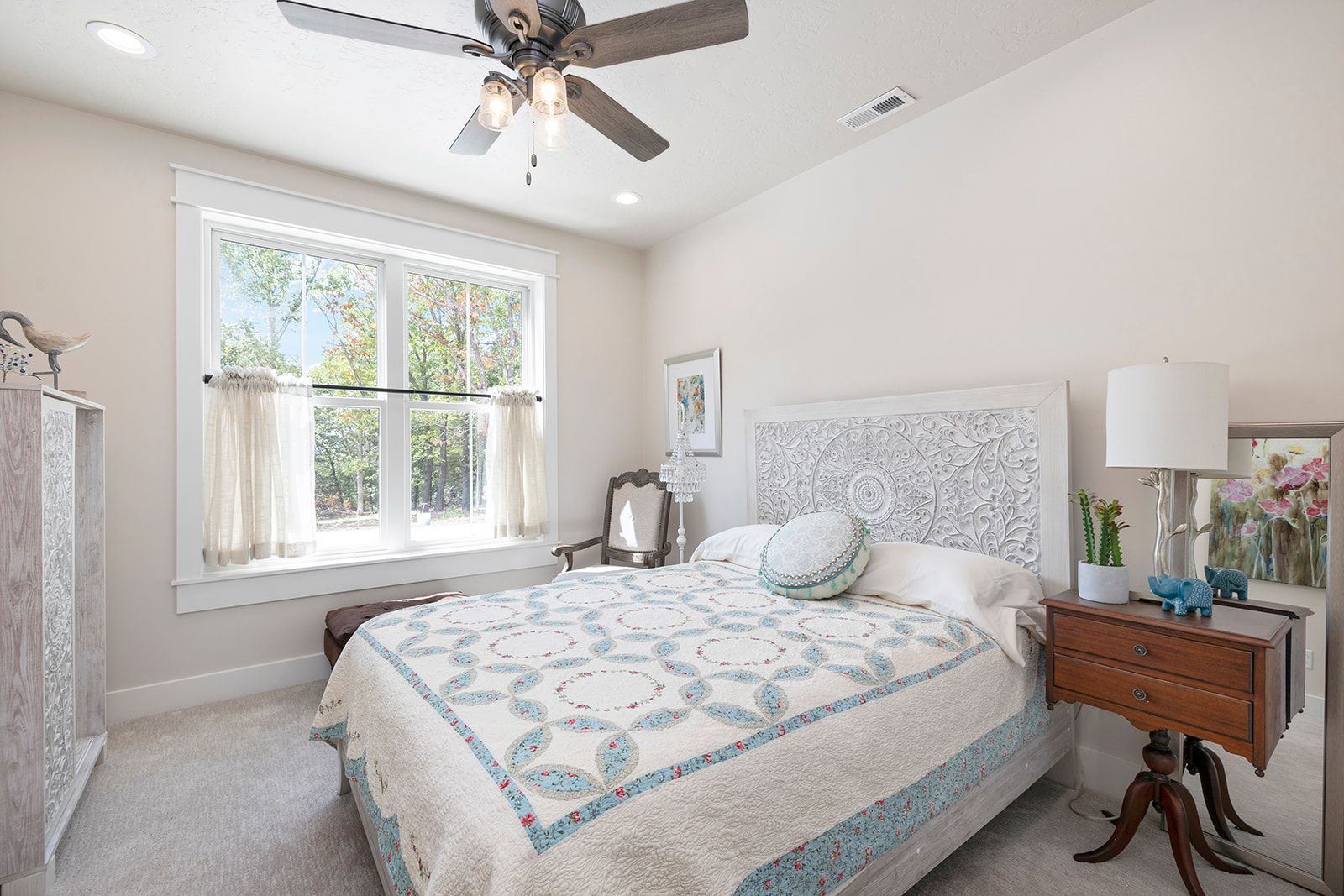 A bedroom with a bed , nightstand , lamp and ceiling fan.