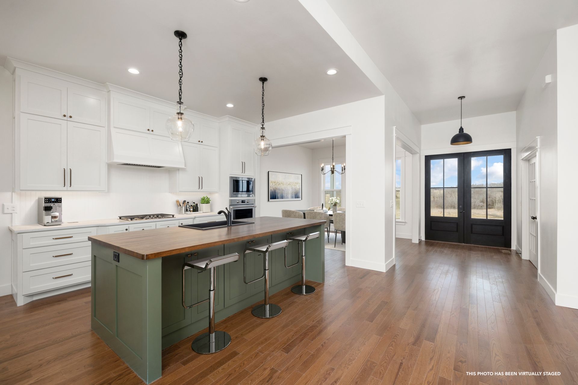 A kitchen with white cabinets and a green island.